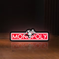 Front view of Monopoly Money Bag LED lightbox sign glowing on a wooden desk