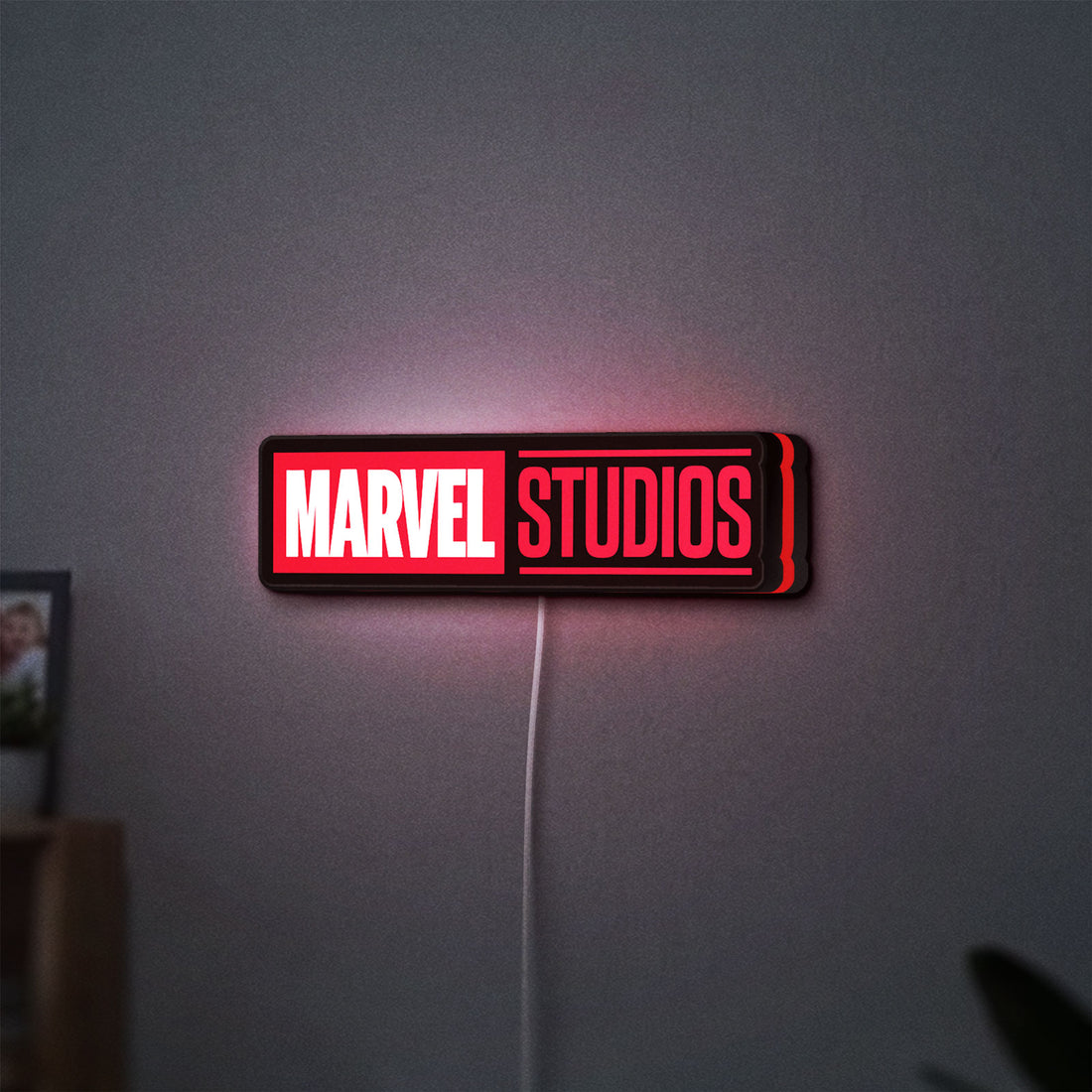 Marvel Studios LED lightbox hanging on a wall with red glow