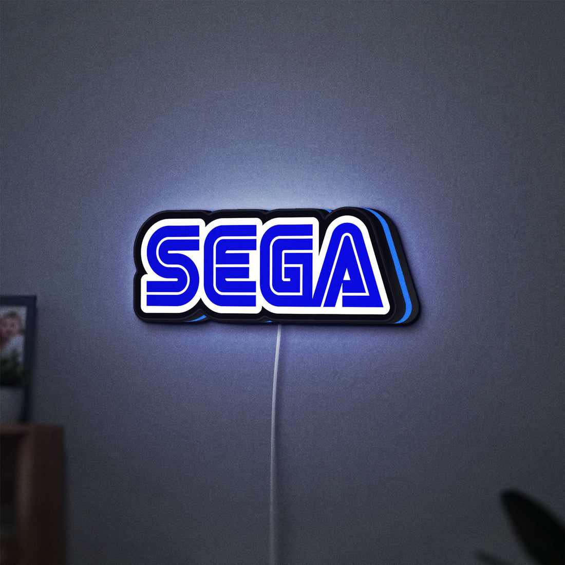 Sega LED lightbox hanging on a wall with blue glow