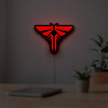 The Last of Us Firefly Logo LED lightbox hanging on a room wall with soft red light