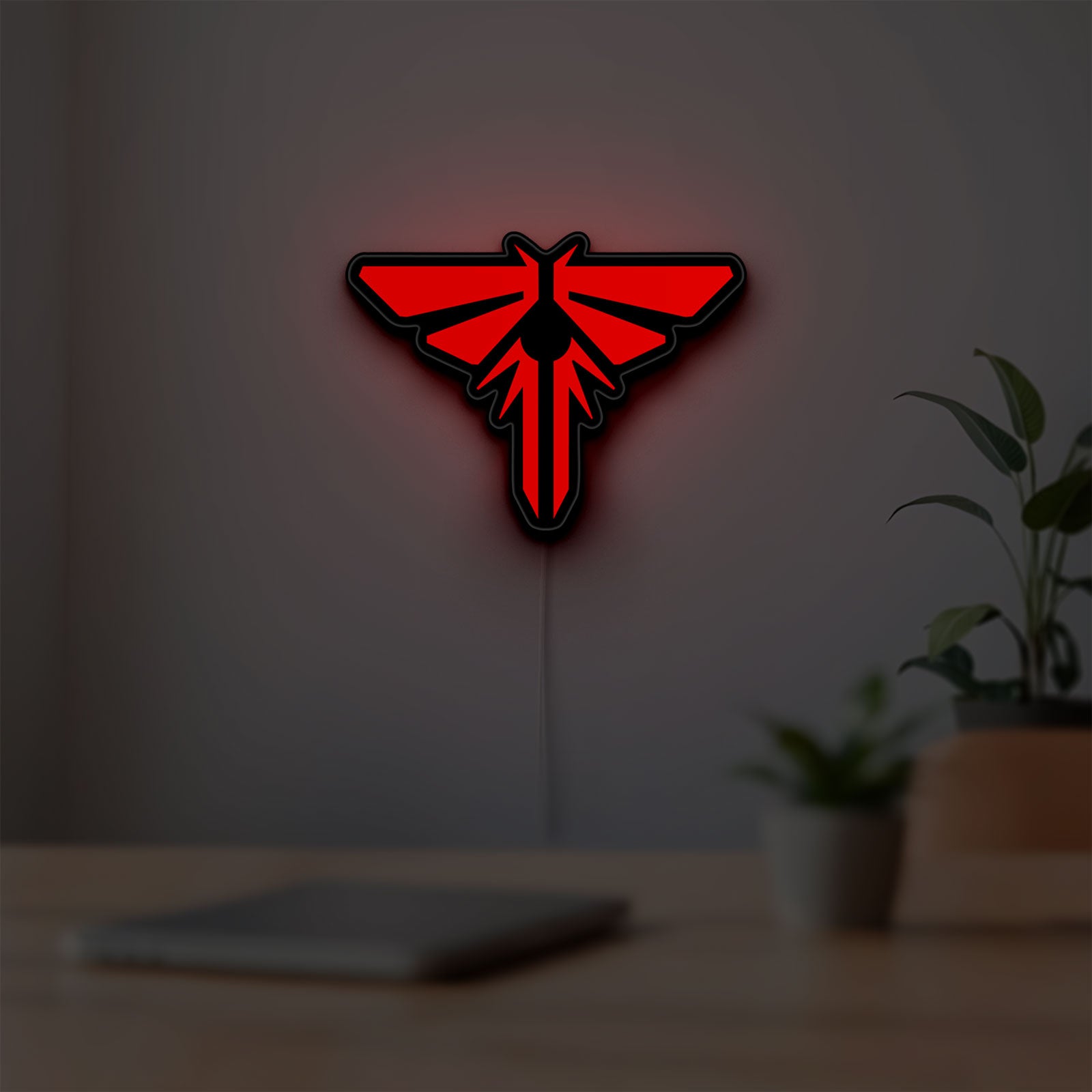 The Last of Us Firefly Logo LED lightbox hanging on a room wall with soft red light