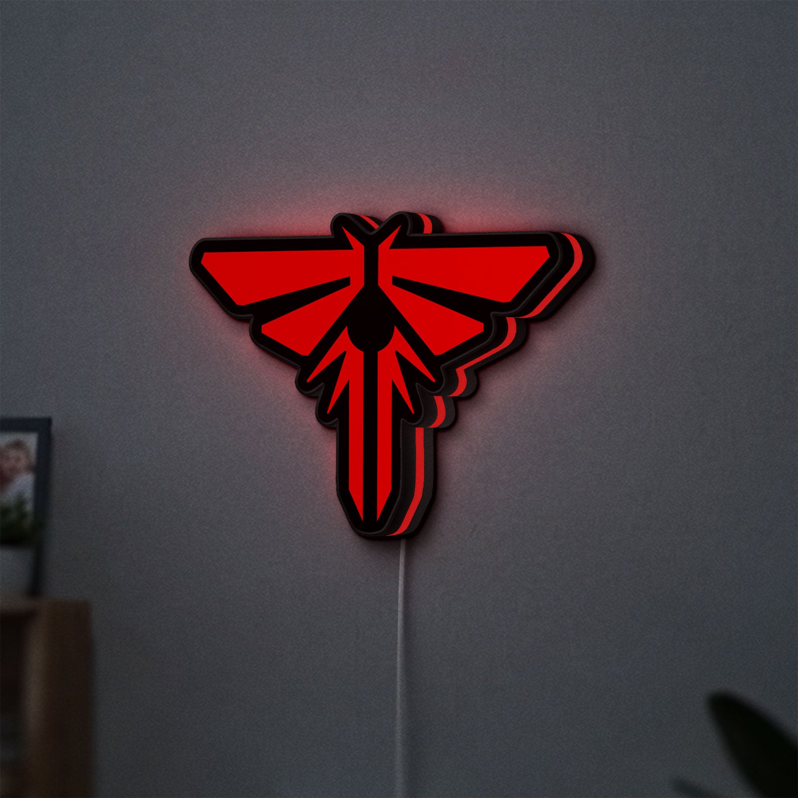 The Last of Us Firefly Logo LED lightbox hanging on a wall with red glow