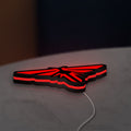 The Last of Us Firefly Logo LED lightbox lying flat on a desk with red glow