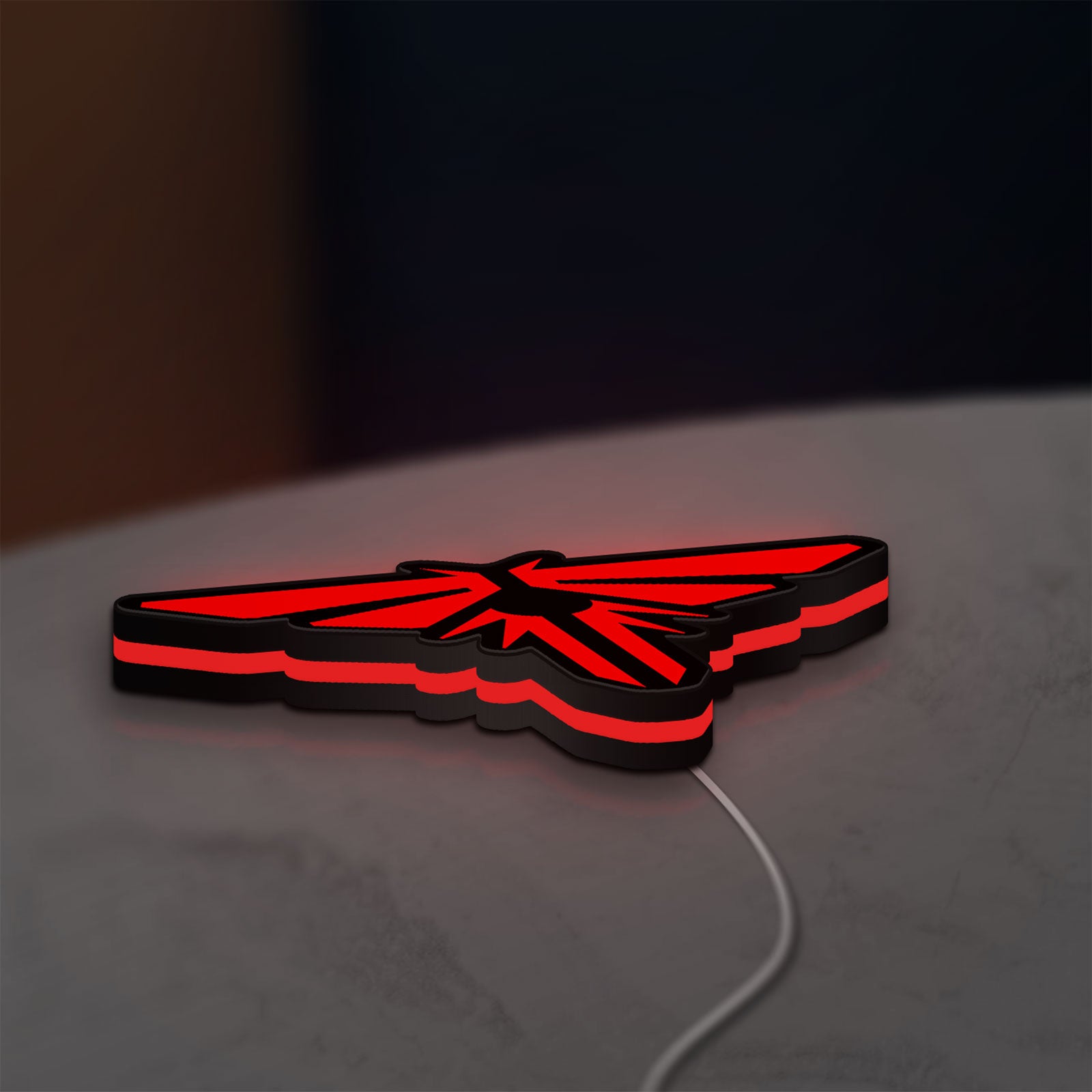 The Last of Us Firefly Logo LED lightbox lying flat on a desk with red glow