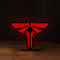 Front view of The Last of Us Firefly Logo LED lightbox sign glowing on a wooden desk
