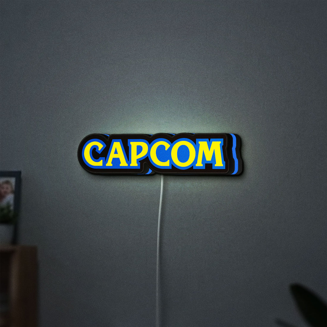 Capcom LED lightbox hanging on a wall with blue glow