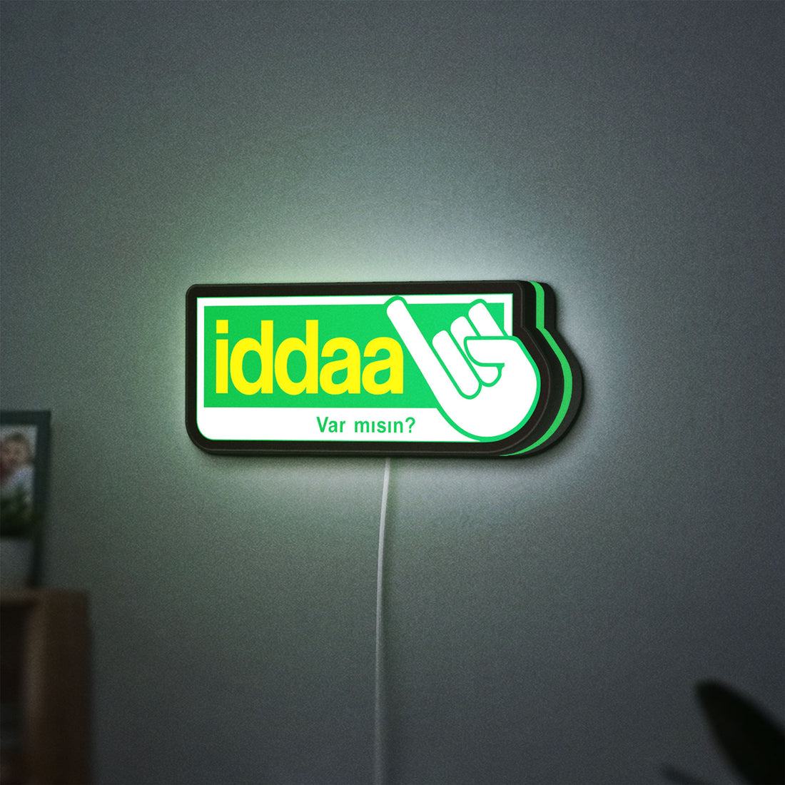 Iddaa LED lightbox hanging on a wall with green glow