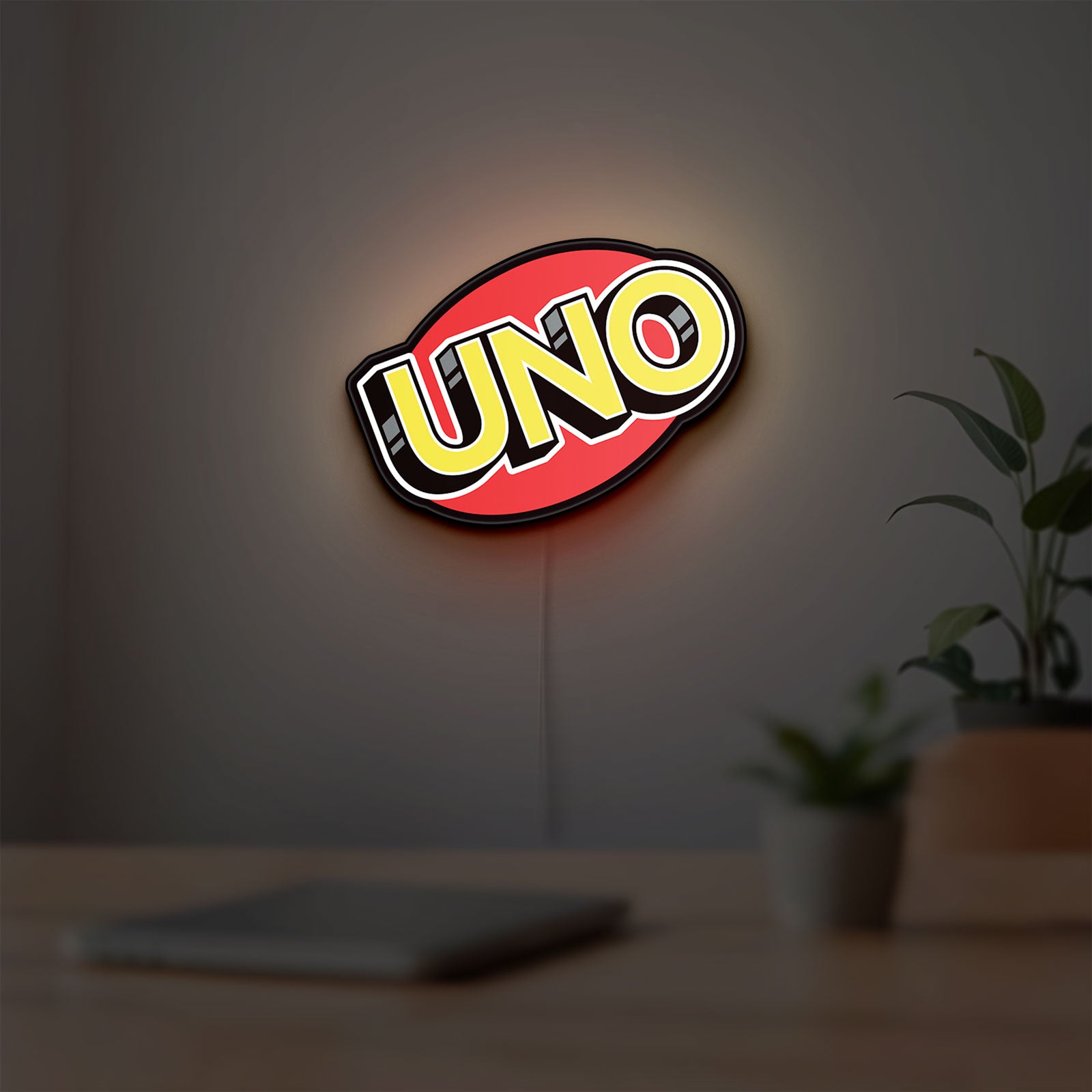 UNO Wild Draw Four LED lightbox hanging on a room wall with soft yellow light