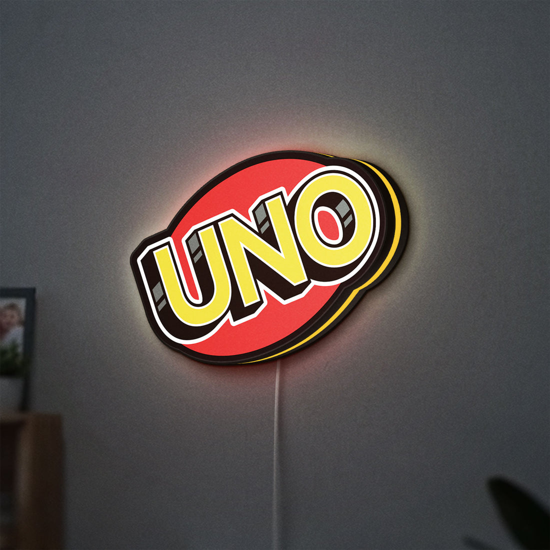 UNO Wild Draw Four LED lightbox hanging on a wall with yellow glow
