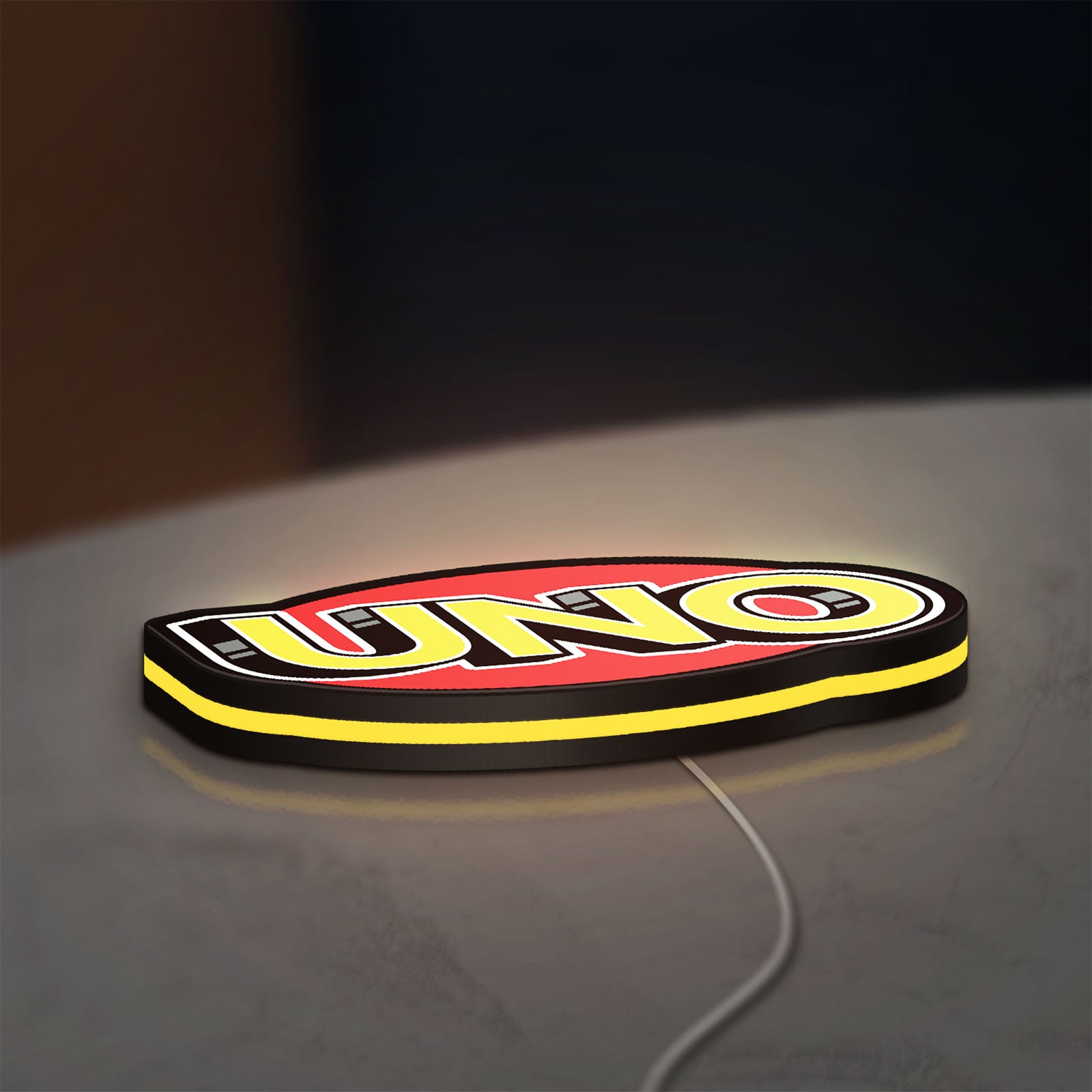 UNO Wild Draw Four LED lightbox lying flat on a desk with yellow glow