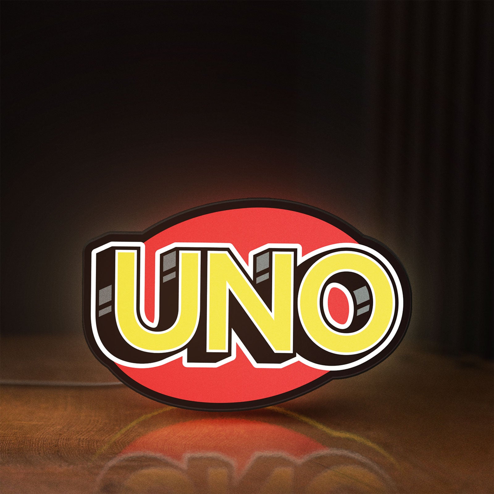 Front view of UNO Wild Draw Four LED lightbox sign glowing on a wooden desk