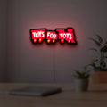 Toys For Tots Train LED lightbox hanging on a room wall with soft red light