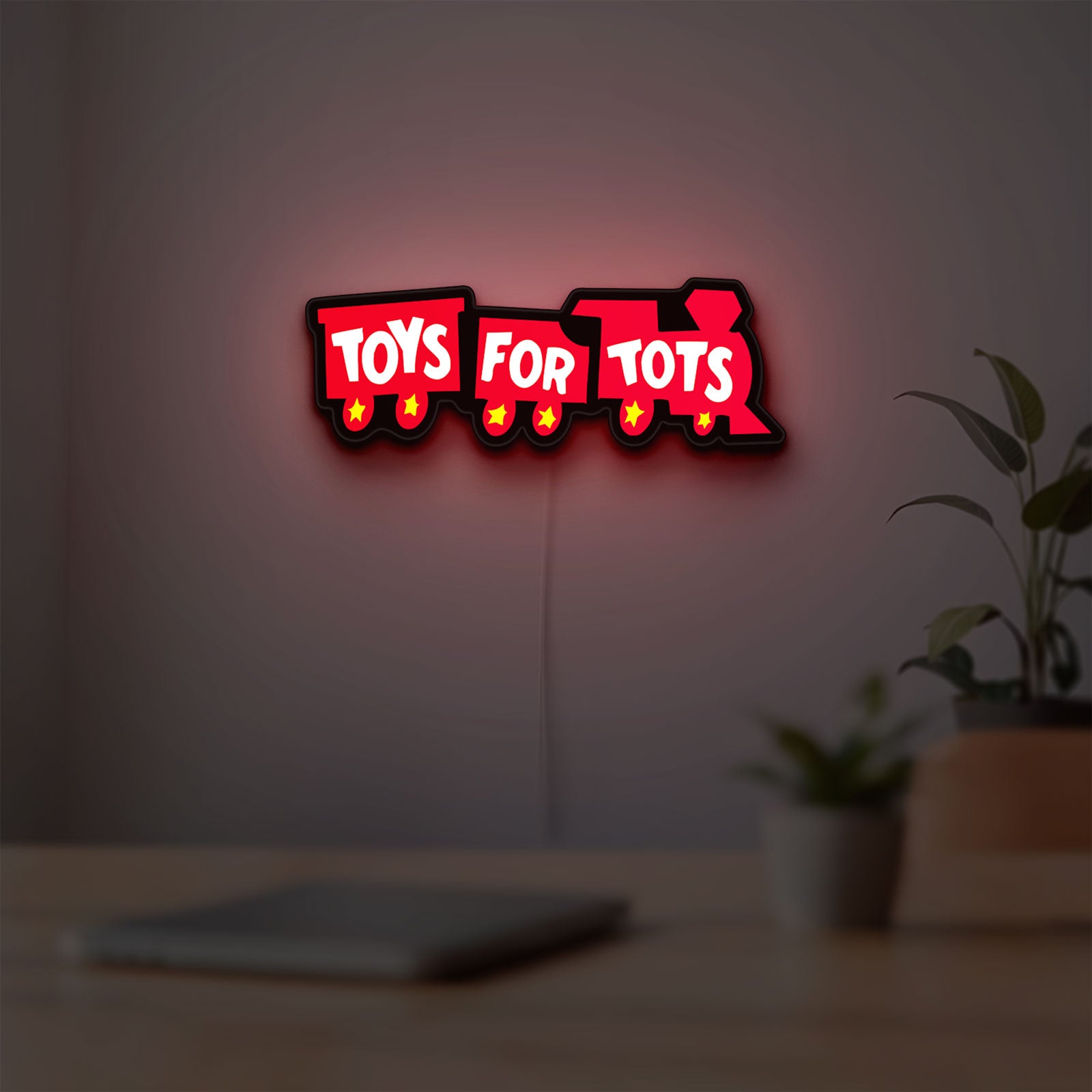 Toys For Tots Train LED lightbox hanging on a room wall with soft red light