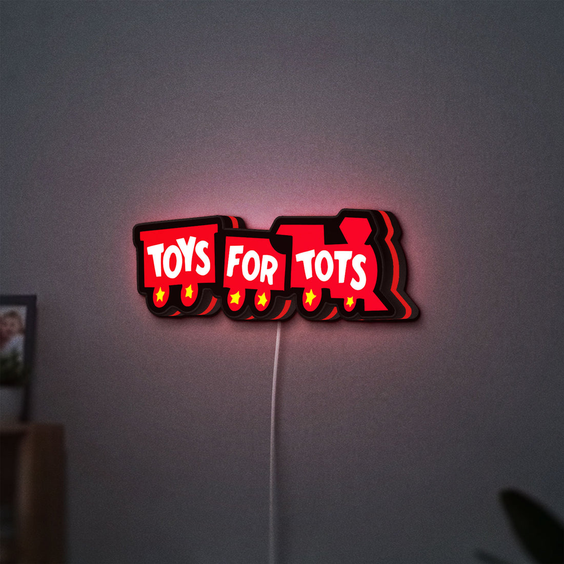 Toys For Tots Train LED lightbox hanging on a wall with red glow