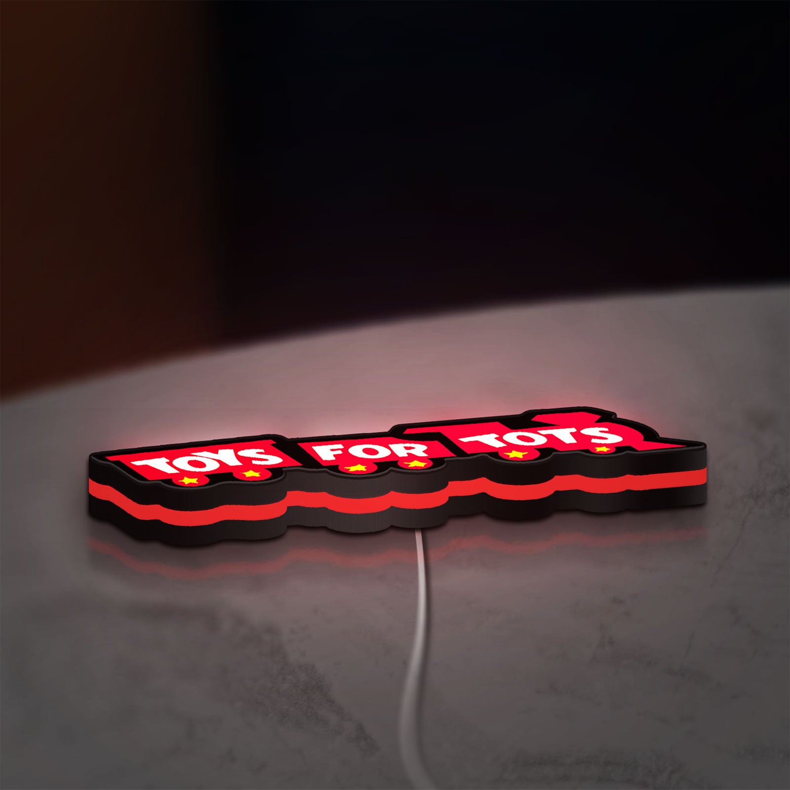 Toys For Tots Train LED lightbox lying flat on a desk with red glow