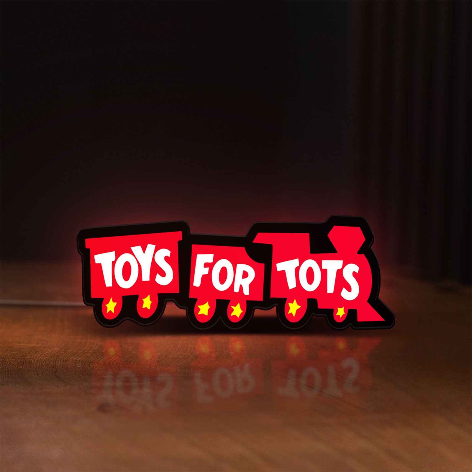 Front view of Toys For Tots Train LED lightbox sign glowing on a wooden desk