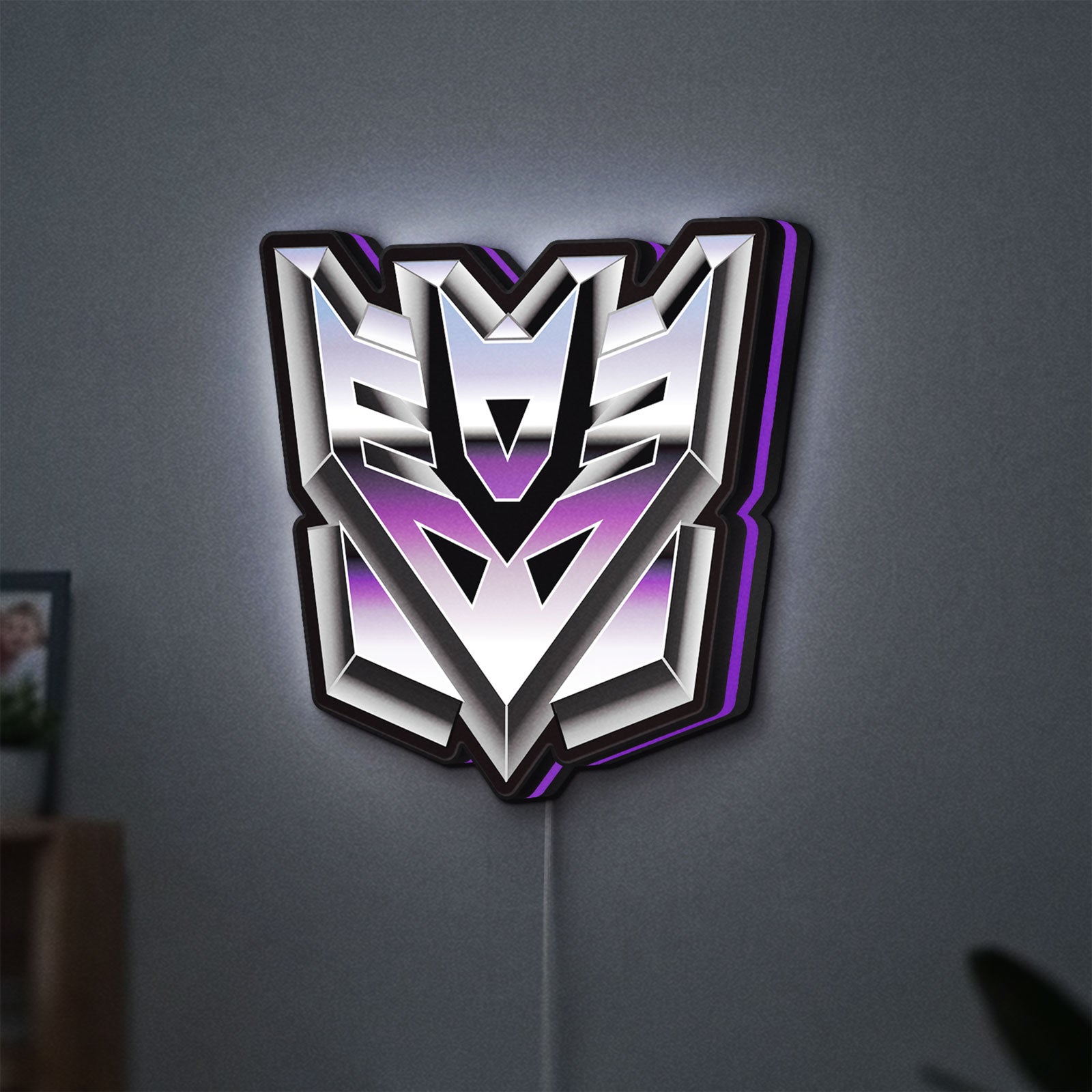 Decepticon LED lightbox hanging on a wall with purple glow