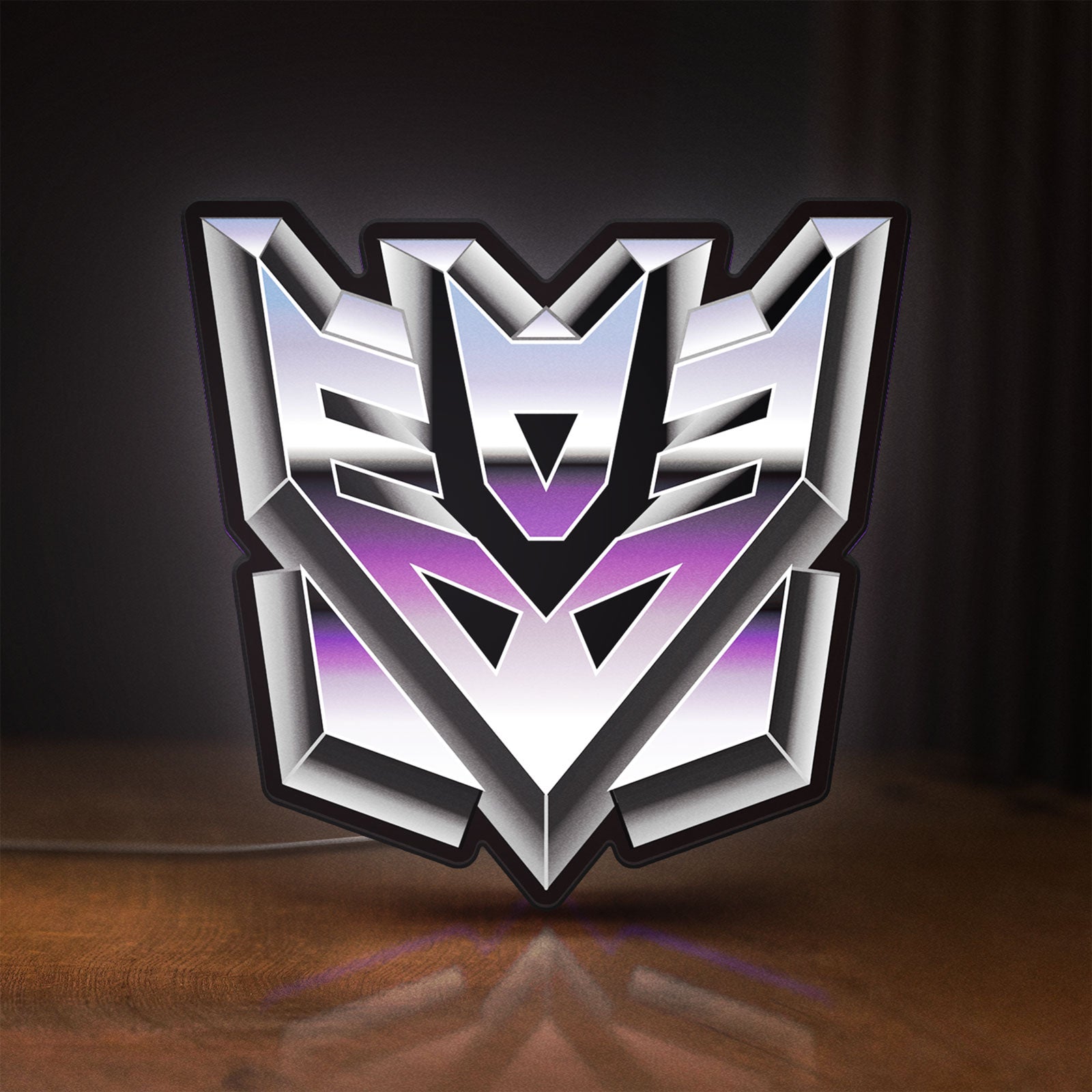 Front view of Decepticon LED lightbox sign glowing on a wooden desk