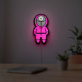 Squid Game LED lightbox hanging on a room wall with soft pink light