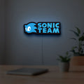 Sonic Team LED lightbox hanging on a room wall with soft blue light
