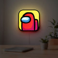 Among Us LED lightbox hanging on a room wall with soft yellow light