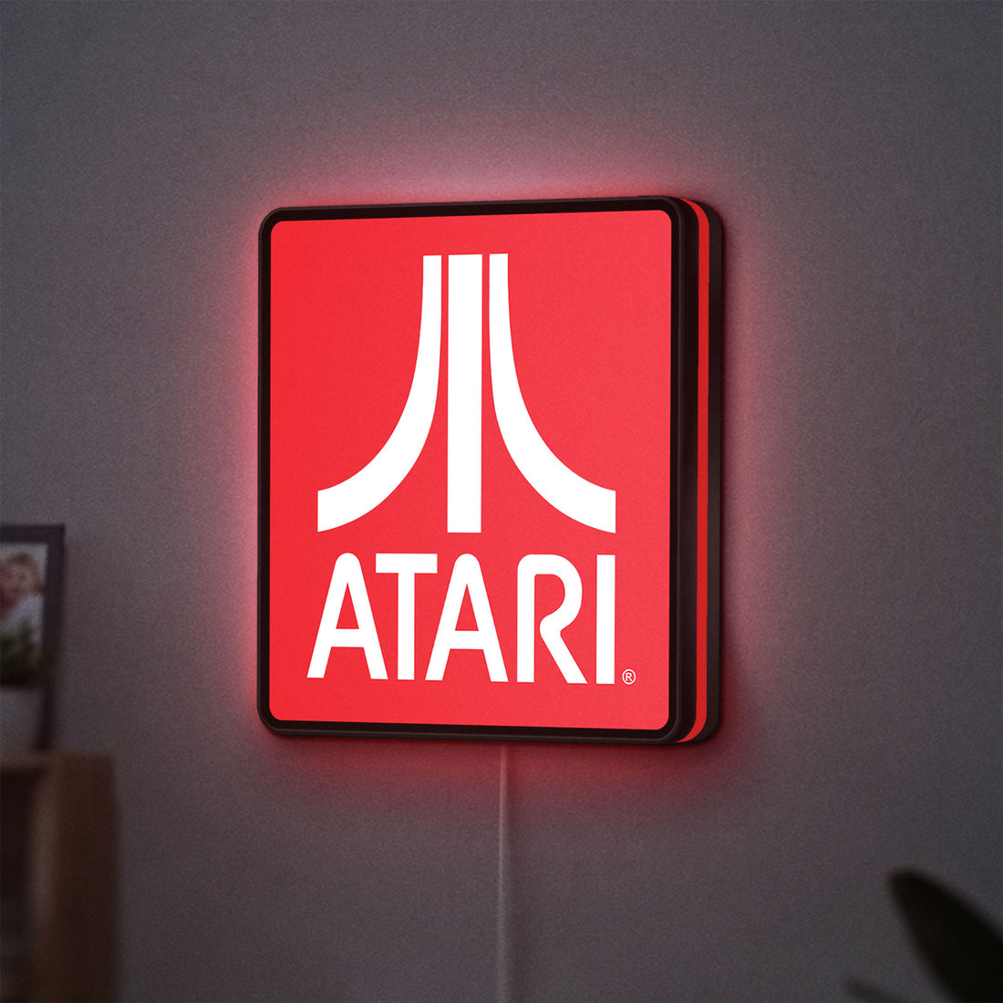 Atari LED lightbox hanging on a wall with red glow