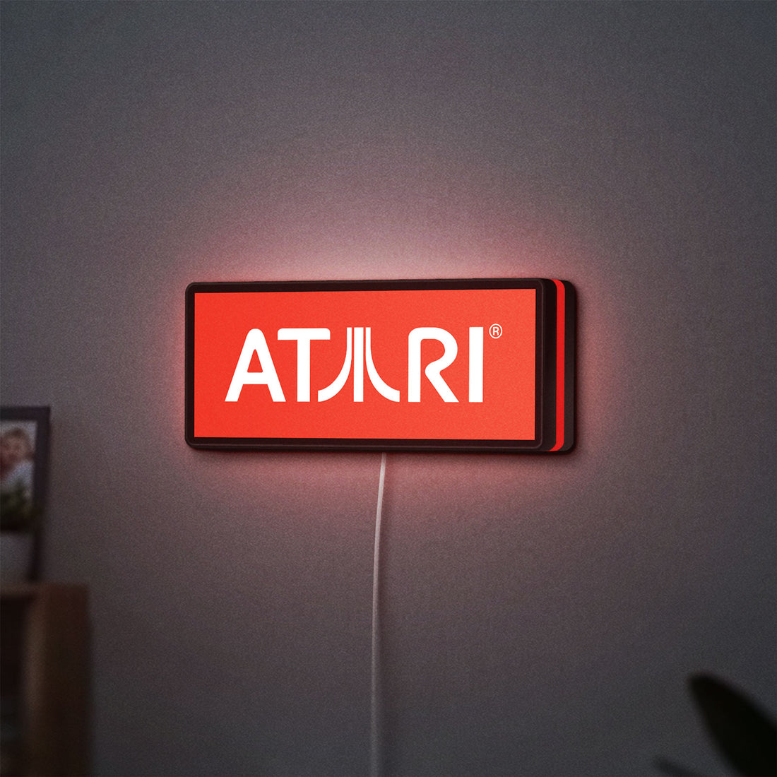 Atari LED lightbox hanging on a wall with red glow