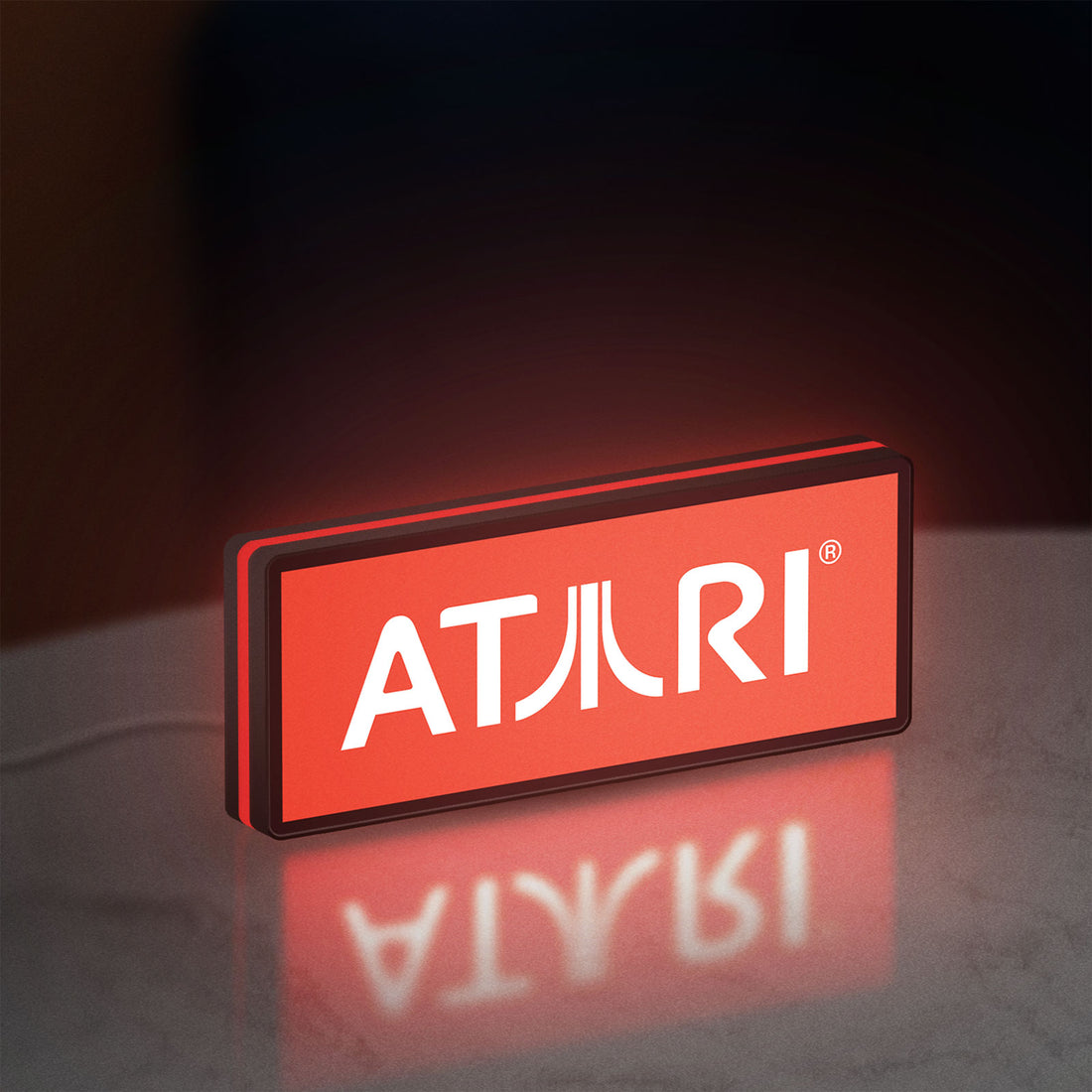 Atari LED lightbox hanging on a wall with red glow