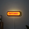 Matchbox LED lightbox hanging on a wall with yellow glow