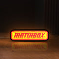 Front view of Matchbox LED lightbox sign glowing on a wooden desk