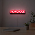 Monopoly Money Bag LED lightbox hanging on a room wall with soft red light