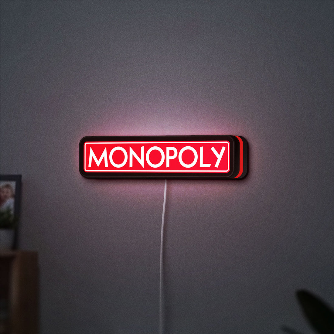 Monopoly Money Bag LED lightbox hanging on a wall with red glow