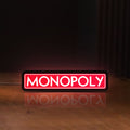 Front view of Monopoly Money Bag LED lightbox sign glowing on a wooden desk