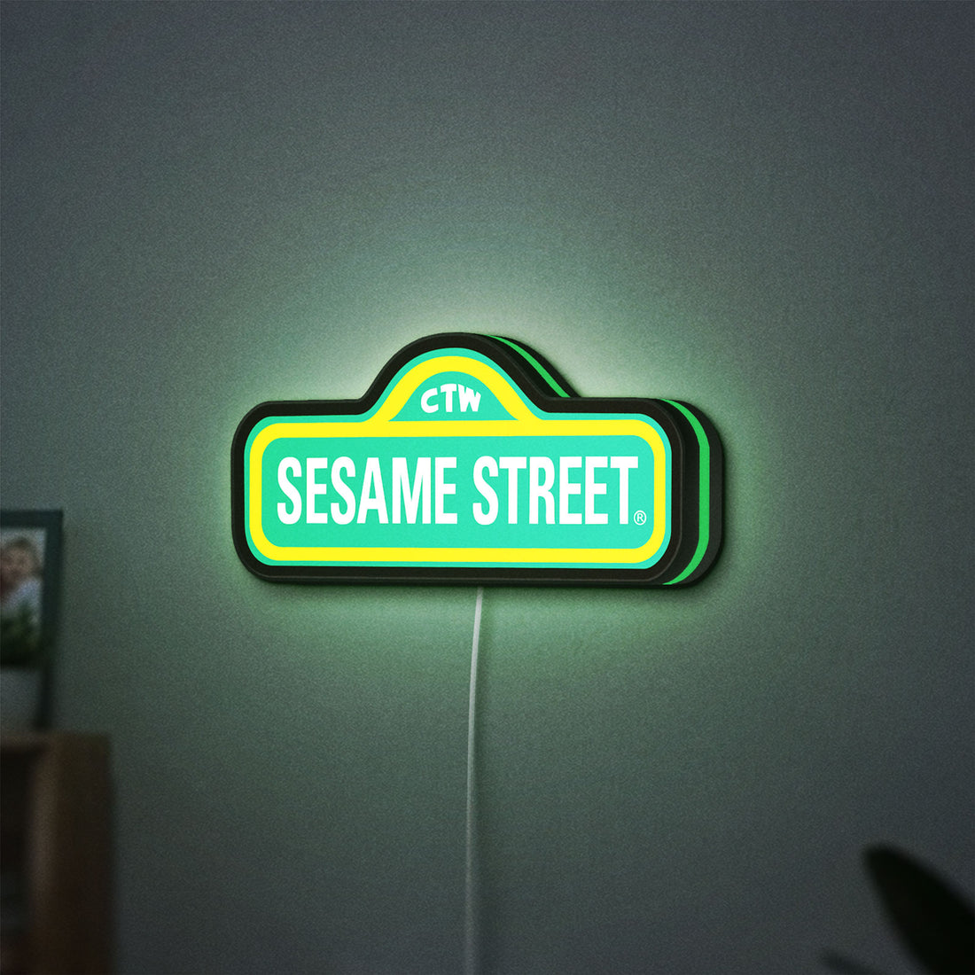 Sesame Street LED lightbox hanging on a wall with green glow