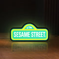 Front view of Sesame Street LED lightbox sign glowing on a wooden desk