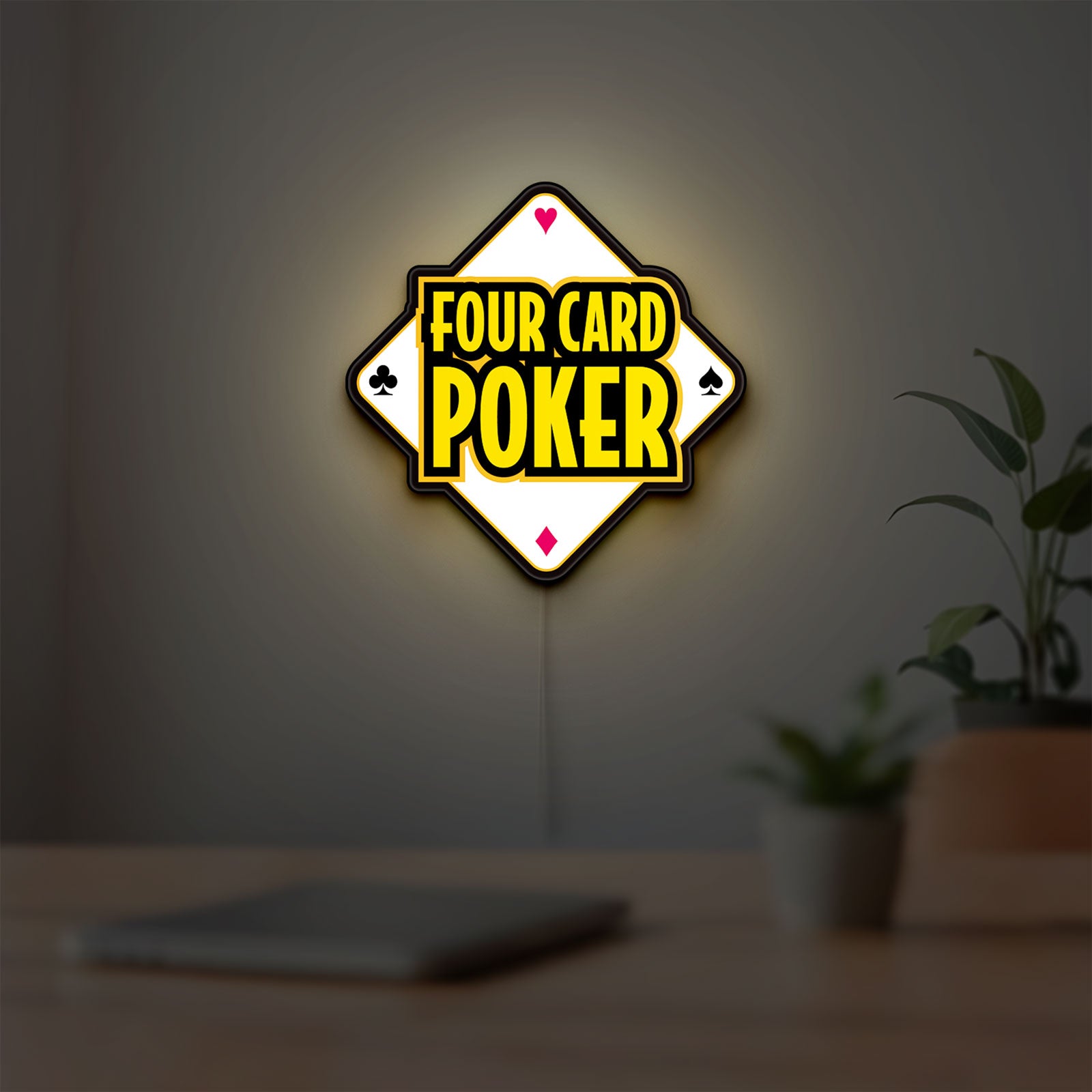 Four Card Poker LED lightbox hanging on a room wall with soft yellow light