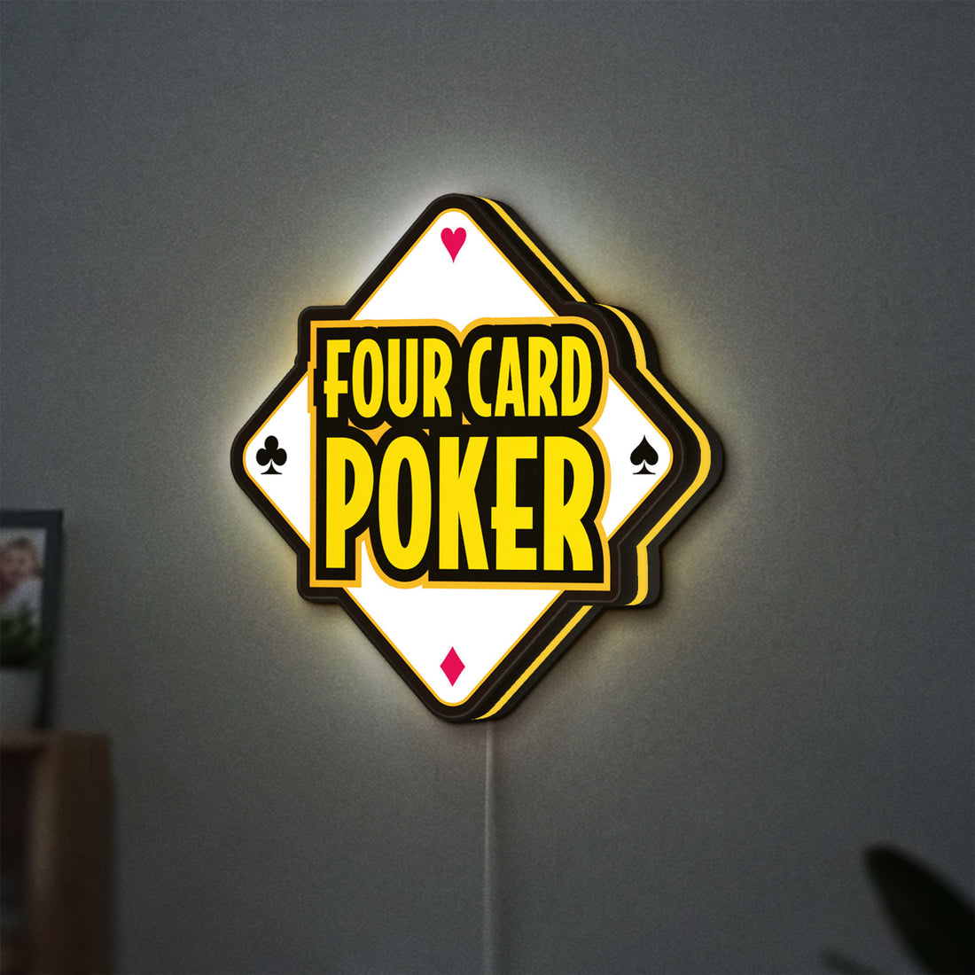 Four Card Poker LED lightbox hanging on a wall with yellow glow