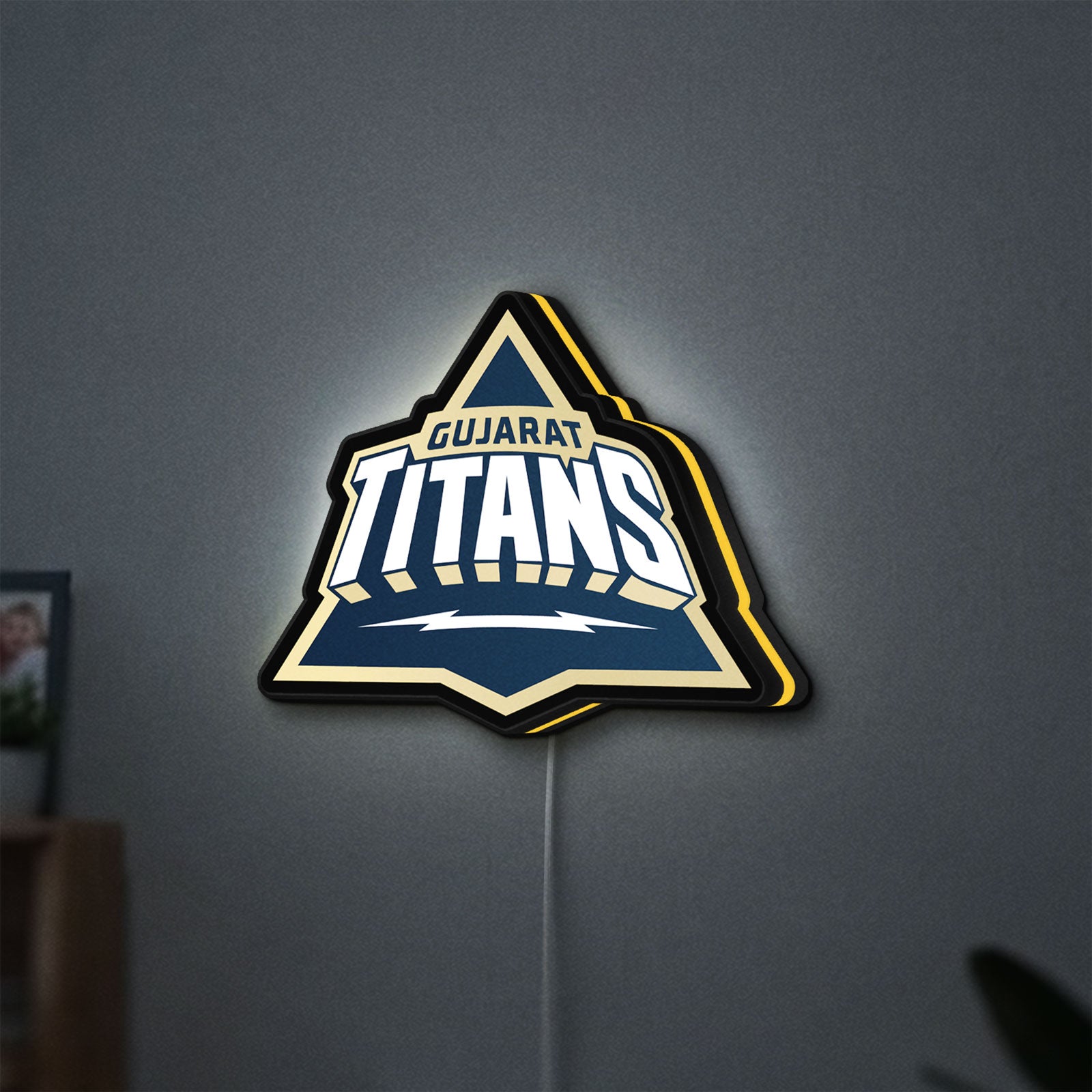 Gujarat Titans LED lightbox hanging on a wall with yellow glow