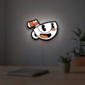 Cuphead LED lightbox hanging on a room wall with soft white light