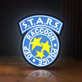 Front view of Raccoon City STARS LED lightbox sign glowing on a wooden desk