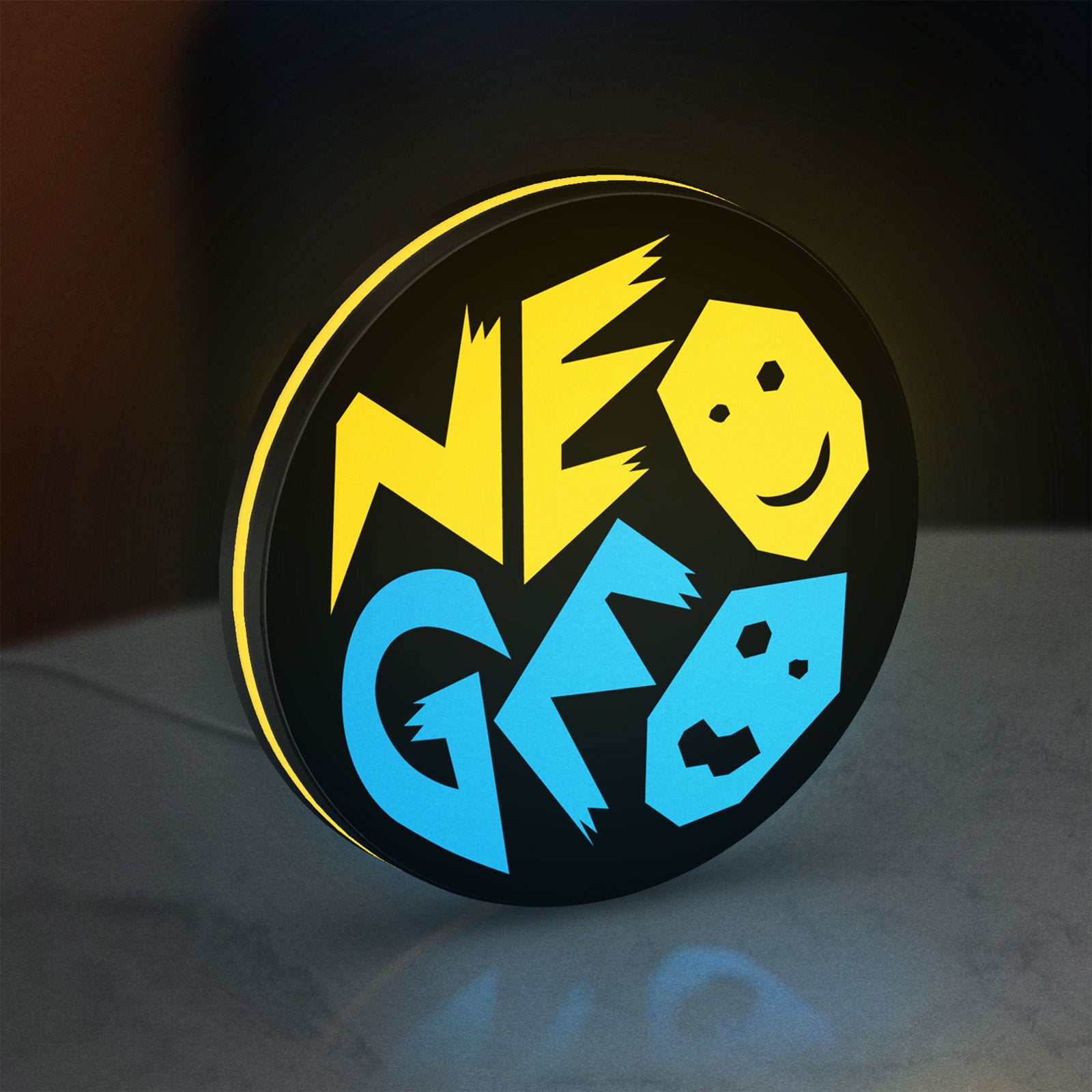 SNK NeoGeo LED lightbox standing on a desk from an angled side view with yellow glow
