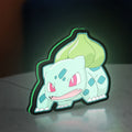 Bulbasaur LED lightbox standing on a desk from an angled side view with green glow