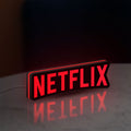 Netflix Style LED lightbox standing on a desk from an angled side view with red glow
