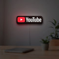 YouTube LED lightbox hanging on a room wall with soft red light
