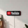 Unlit YouTube LED lightbox mounted on a wall in daylight