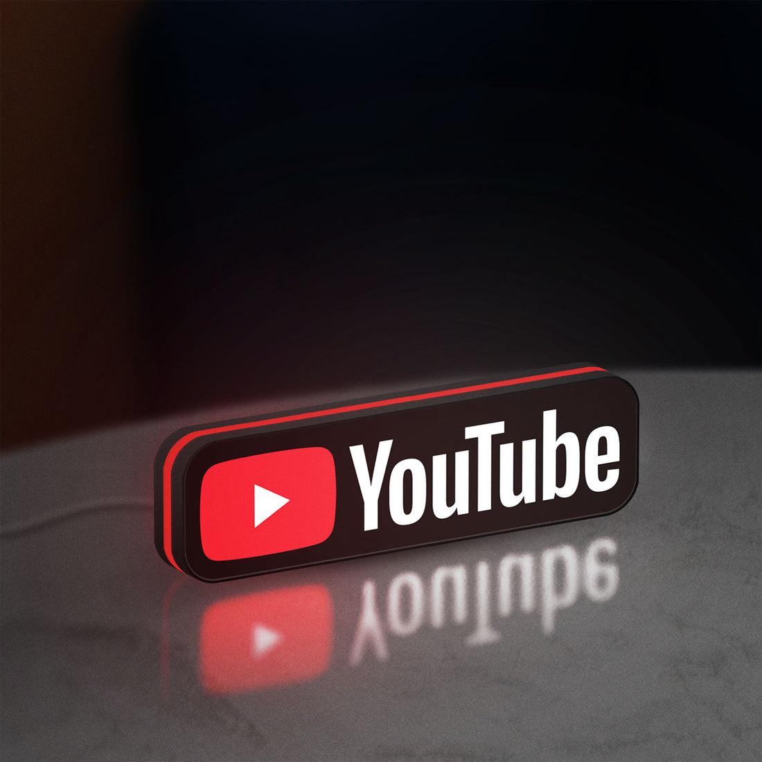 YouTube LED lightbox hanging on a wall with red glow