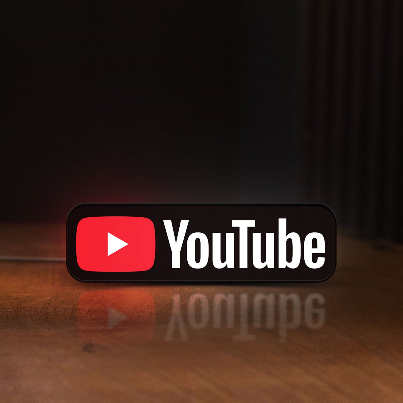 Front view of YouTube LED lightbox sign glowing on a wooden desk