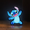 Front view of Stitch Happy LED lightbox sign glowing on a wooden desk