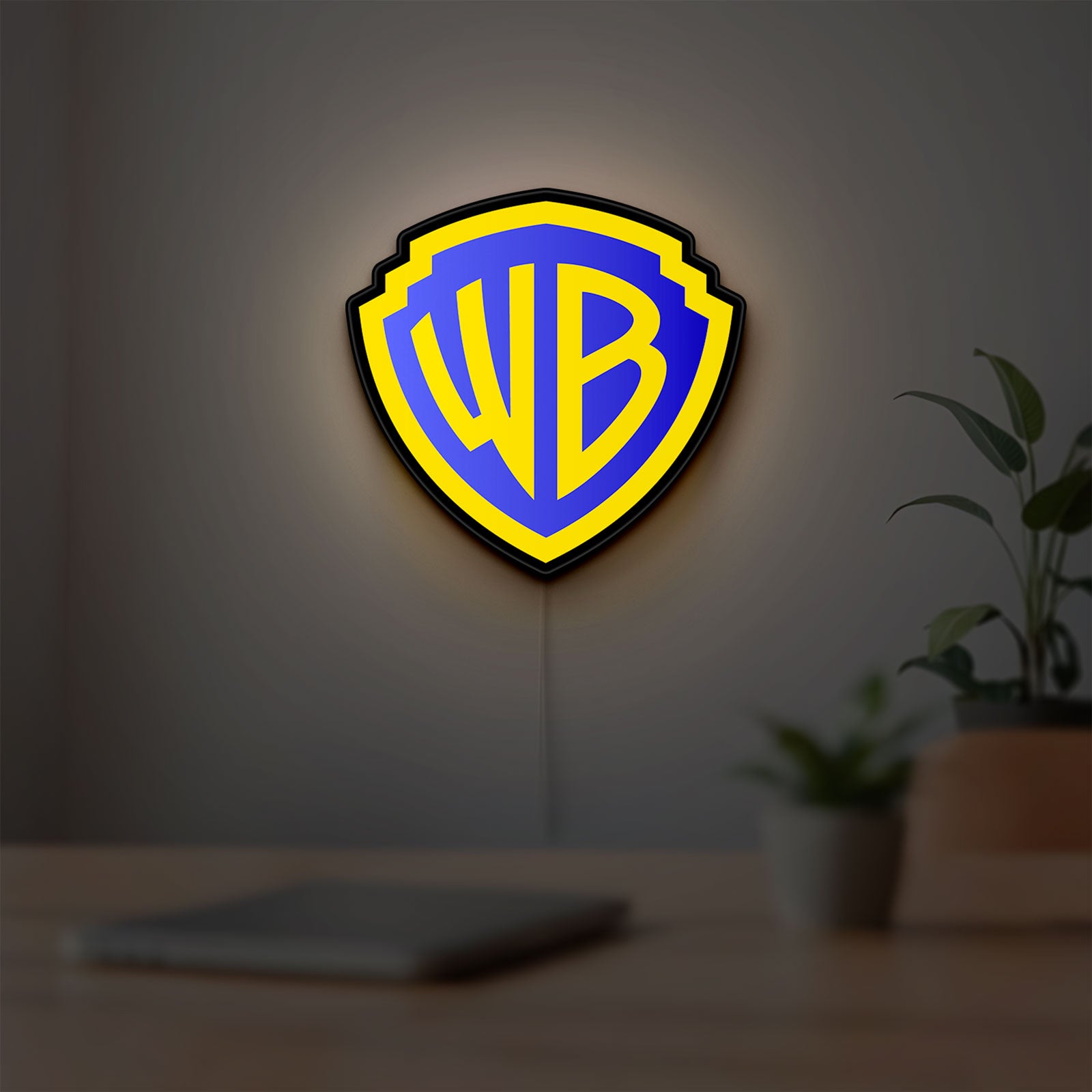 Warner Bros Shield LED lightbox hanging on a room wall with soft yellow light