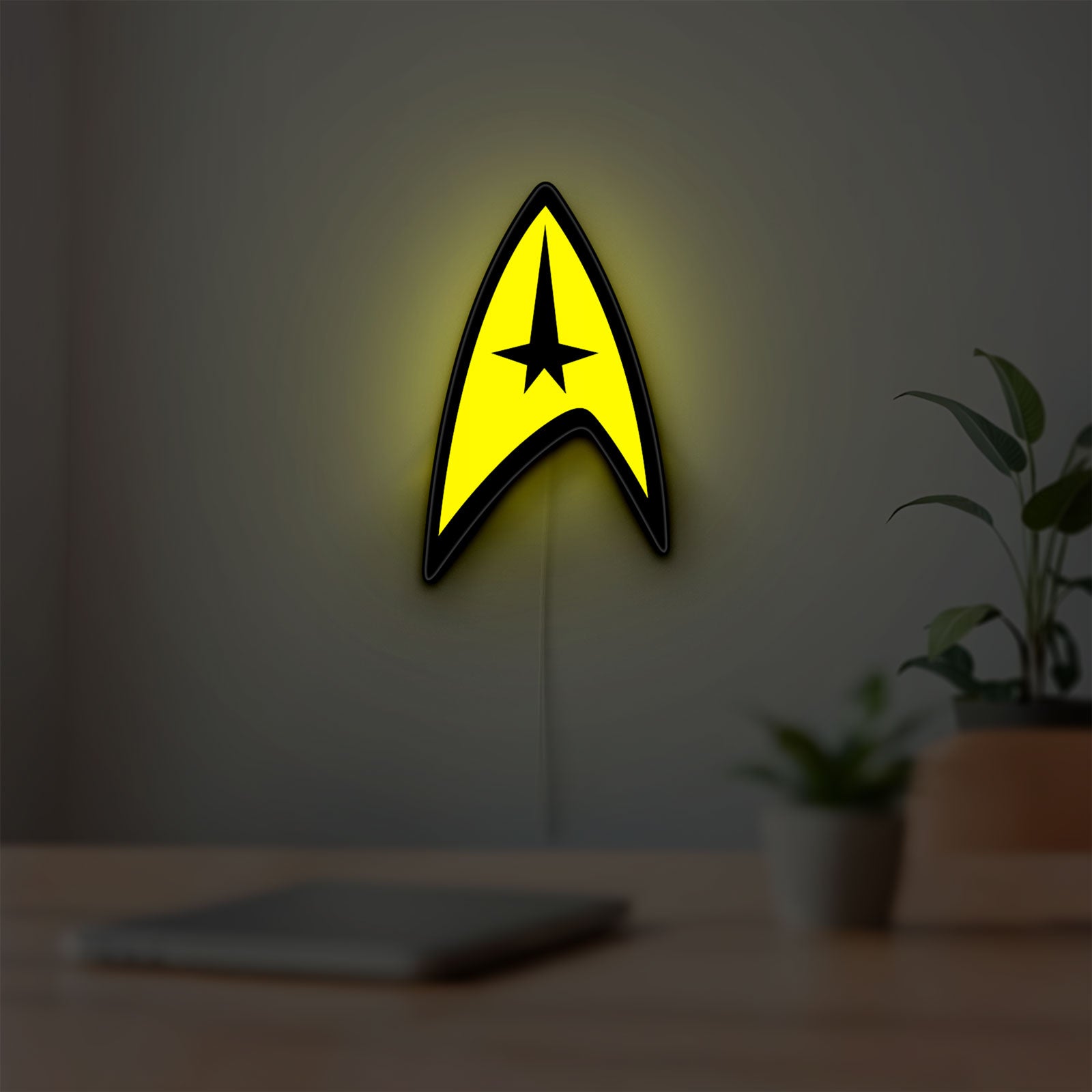 Star Trek Command Insignia LED lightbox hanging on a room wall with soft yellow light